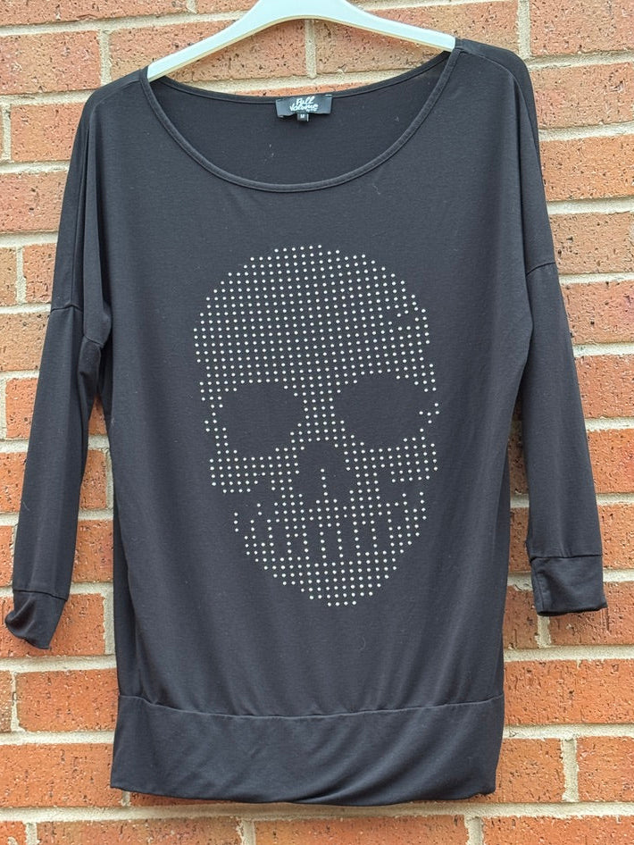 Dark grey EMP sweatshirt with a skull design on a hanger against a brick wall.