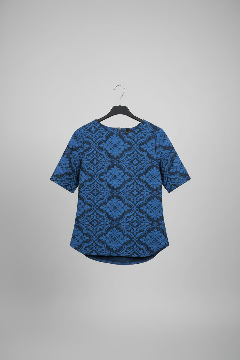 Blue patterned shirt on a hanger against a brick wall