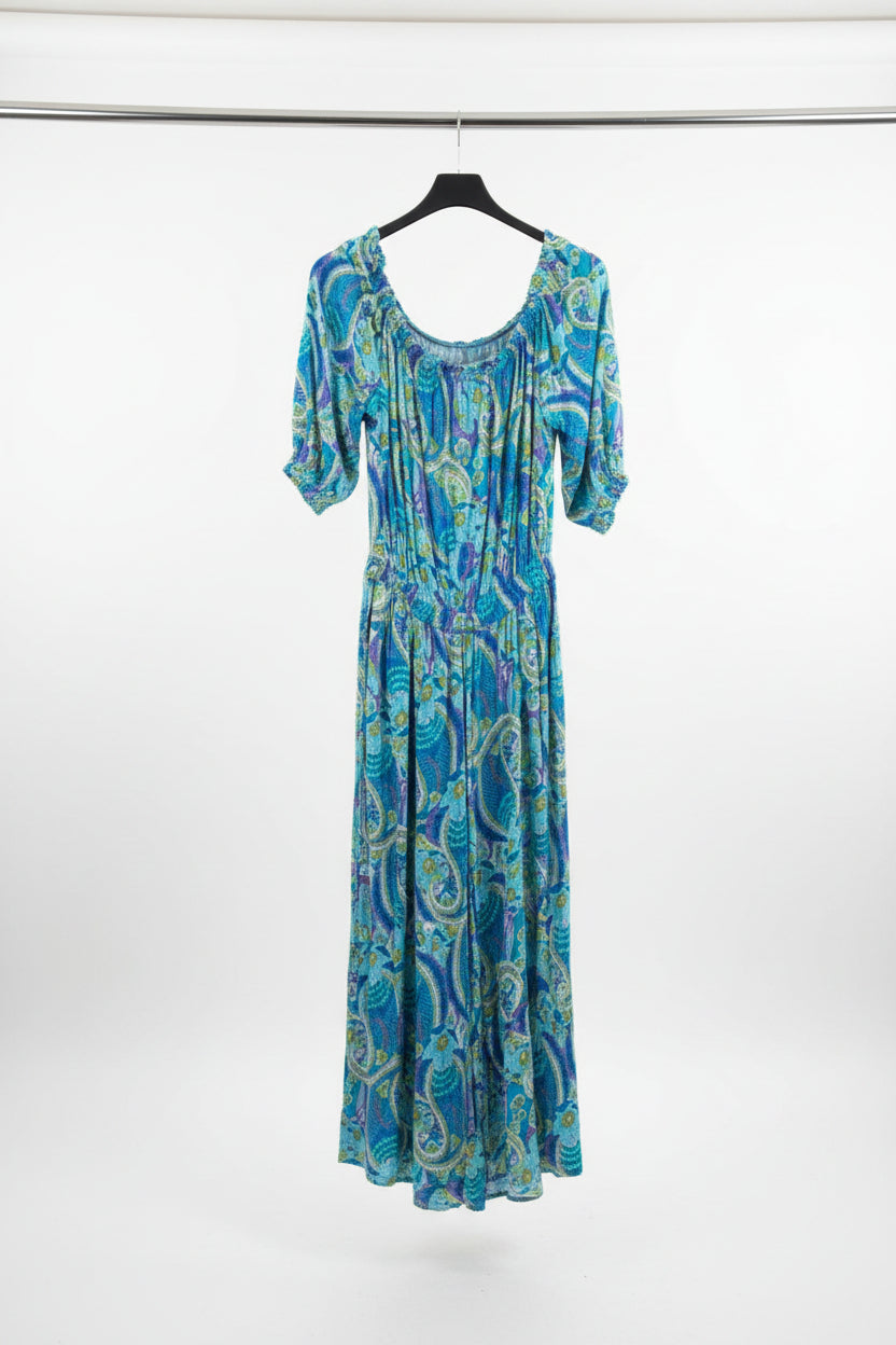 Blue floral dress hanging on a rack against a brick wall